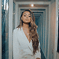 a woman with long hair is standing in a hallway wearing a white suit .