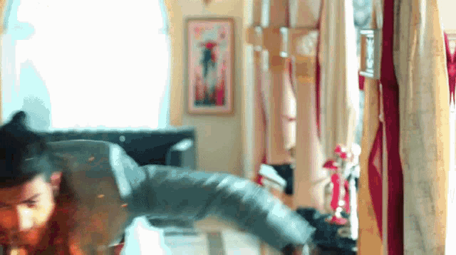 a man is doing a handstand in a living room with a painting on the wall .