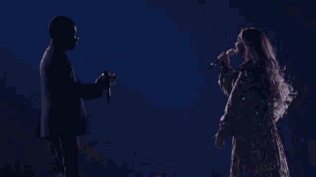 a man and a woman are singing into microphones on stage .