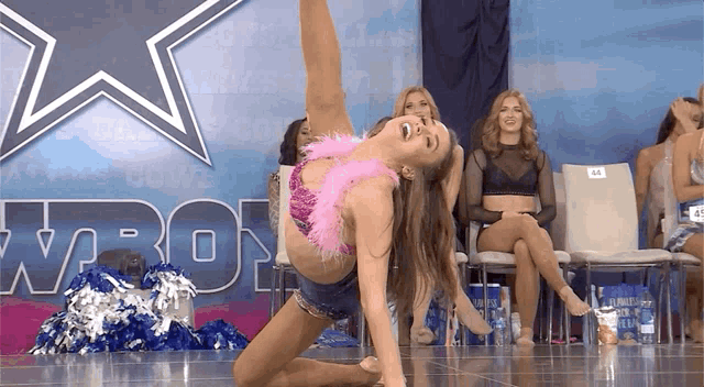 a cheerleader performs in front of a dallas cowboys sign