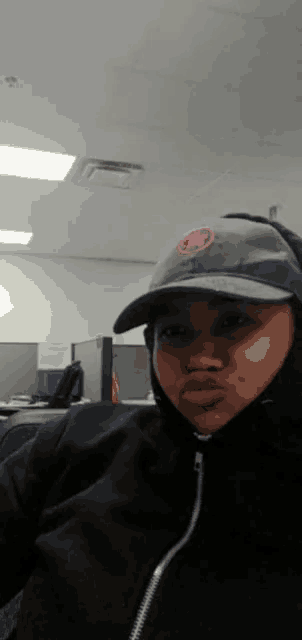 a woman wearing a hat and a hoodie makes a face