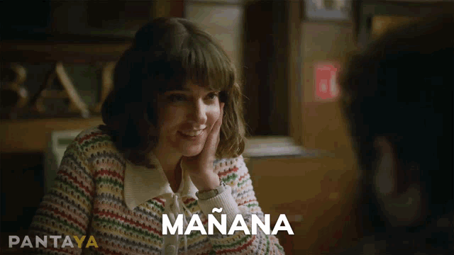 a woman in a colorful sweater is smiling and the word mañana is behind her