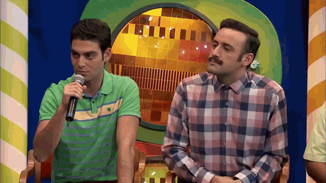 a man speaking into a microphone next to another man