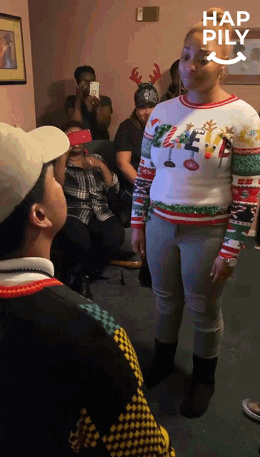 a woman wearing an ugly christmas sweater stands in front of a crowd