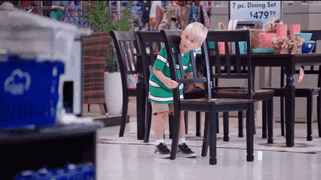 a little boy stands in front of a dining set for $ 499.99