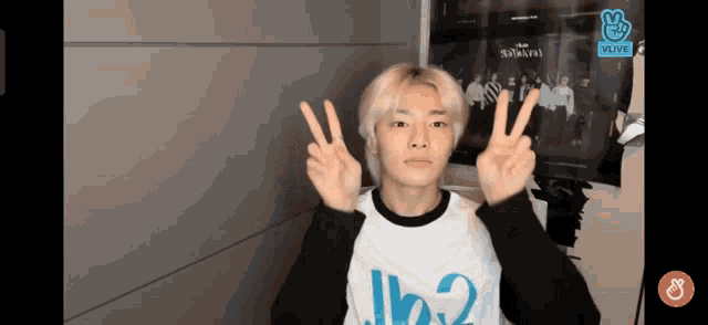 a young man is giving a peace sign in front of a vlive sign