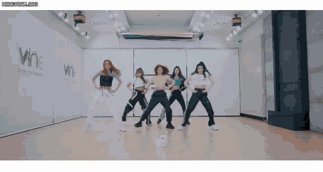 a group of women are dancing in a room with a sign that says wine entertainment