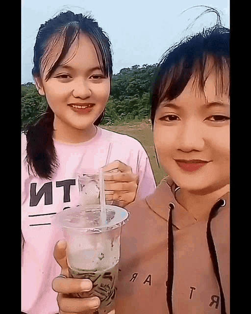 a girl in a pink shirt that says ит holds a cup of liquid