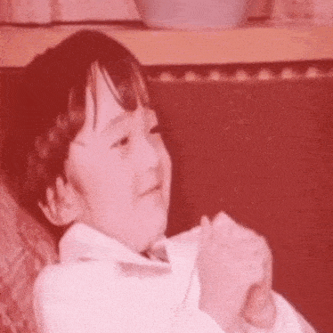 a young boy is sitting on a couch with his hands folded in front of him .