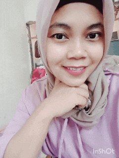 a woman wearing a hijab and a purple shirt is smiling for the camera