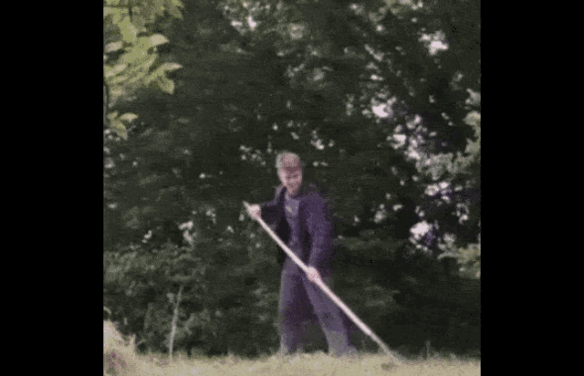 a man is standing in the grass holding a stick