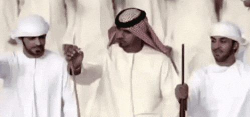 a group of men are standing in a line holding sticks and ropes .