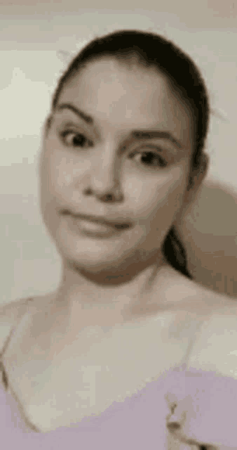 a woman in a purple tank top is taking a selfie and smiling for the camera .