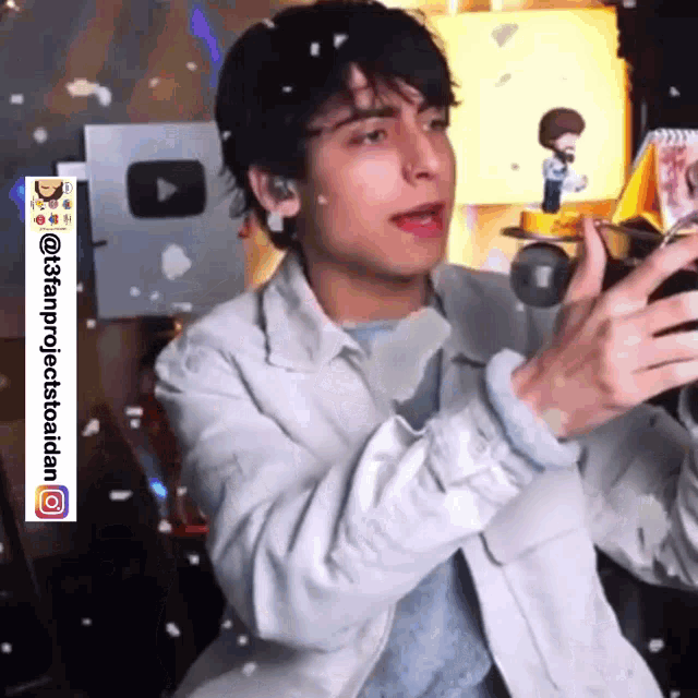 a young man in a white jacket is holding a cup in his hand and making a funny face .