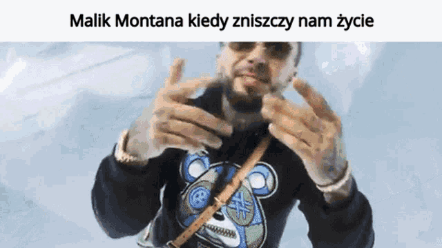 a man wearing a black shirt with a teddy bear on it and the words malik montana kiedy zniszczy nam zycie