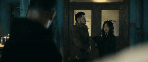 a man and a woman are standing in front of a door that says ' lighting '