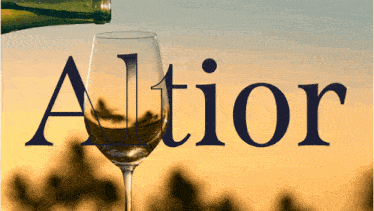 a bottle of wine is poured into a wine glass and the word altior is visible