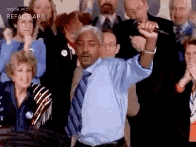 a man in a blue shirt and tie is dancing in front of a crowd while holding a microphone .