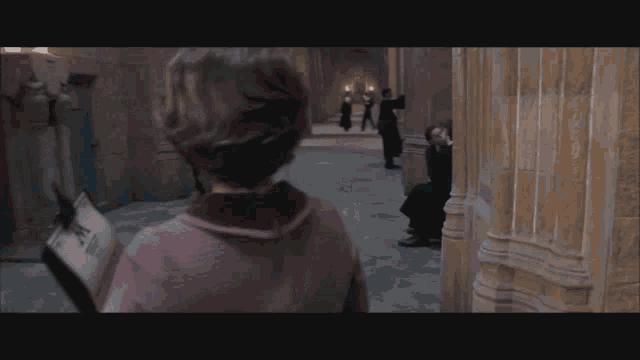a woman in a pink sweater is holding a newspaper with the word harry potter on it