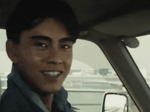 a young man is sitting in a car and smiling