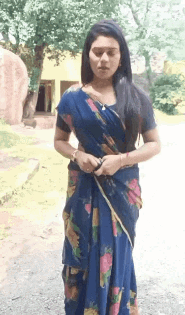 a woman in a blue floral saree stands in front of a building