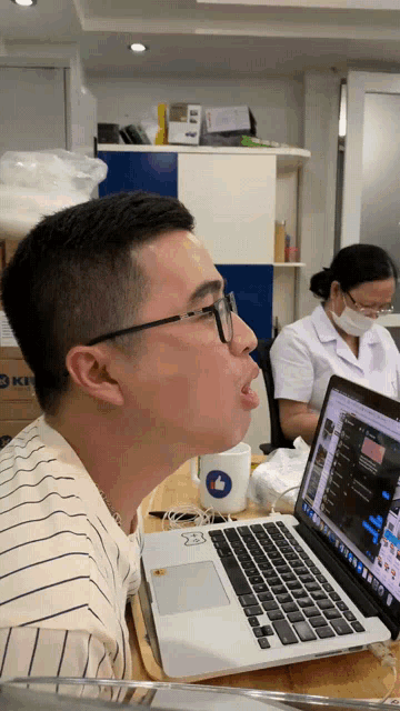 a man sitting in front of a laptop with a sticker on the keyboard that says ' i like '