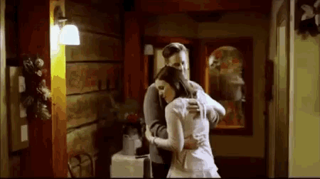 a man is hugging a woman in a hallway in a house .