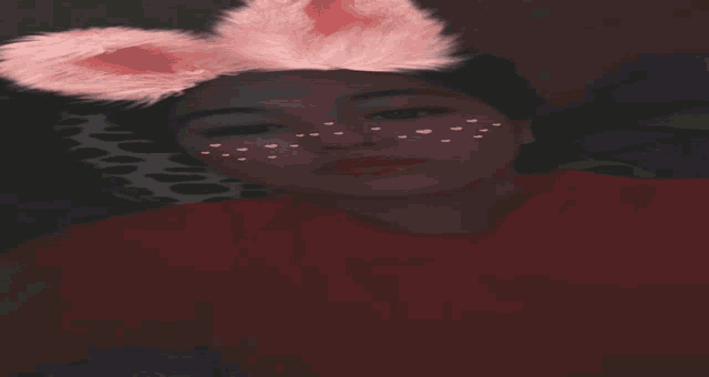 a girl wearing pink bunny ears and a red shirt