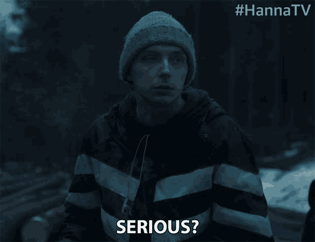 a man in a striped jacket says serious in a dark room