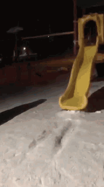a yellow slide in a sandy area at night