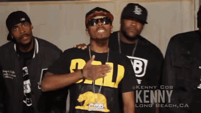 a group of men are posing for a picture and one of them is kenny