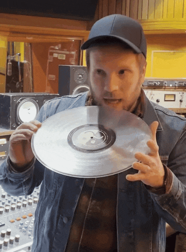 a man in a hat holds a record in his hand