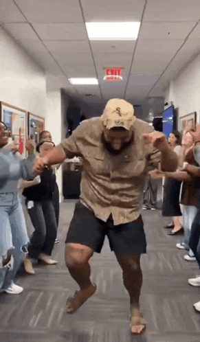 a man is dancing in a hallway with a group of people behind him .
