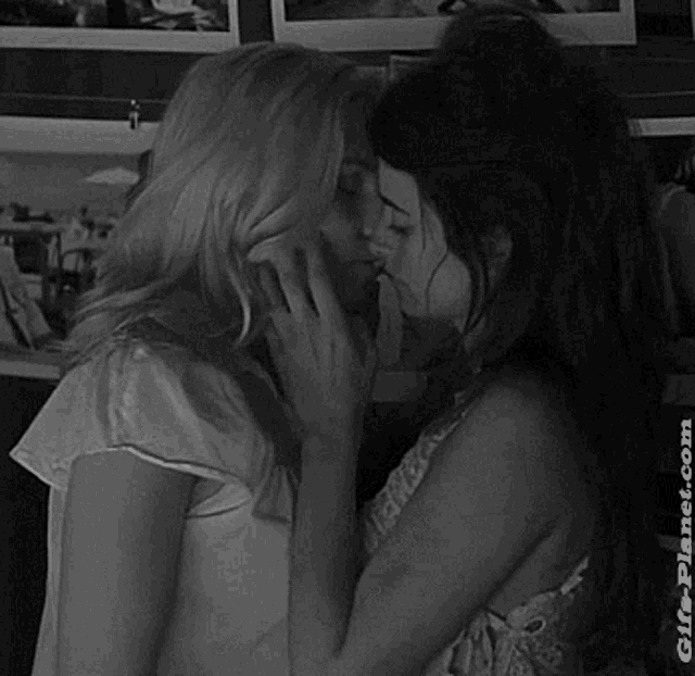 a black and white photo of two women kissing