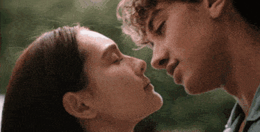 a close up of a man and woman kissing with their eyes closed