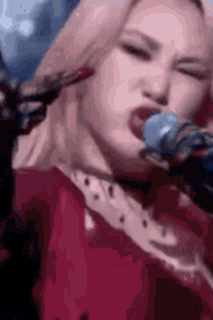 a woman is singing into a microphone with a knife in her mouth .