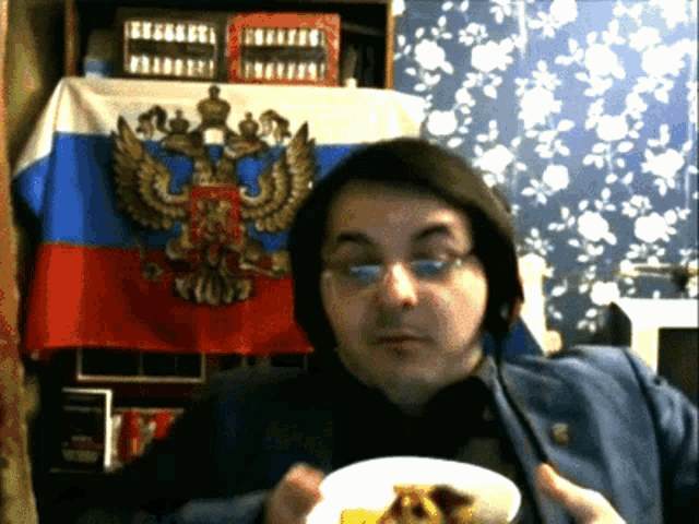 a man is eating a plate of food in front of a flag that says russia