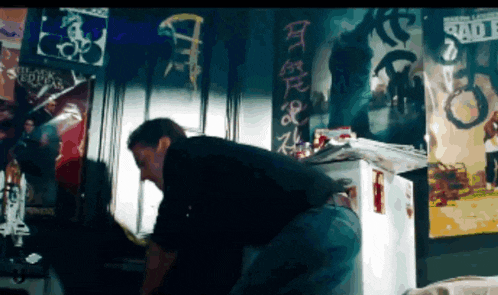 a man is standing in front of a wall with posters on it including one that says ' slayer '