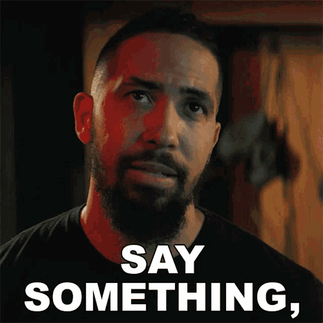 a man with a beard and a black shirt says say something