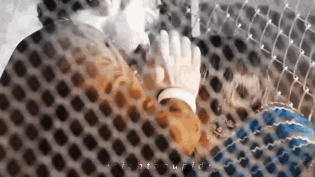 a man and a woman are holding hands behind a net .