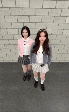 two girls in school uniforms are standing next to each other