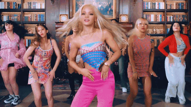 a group of women are dancing in front of a bookshelf with one wearing a shirt that says ' i love you '