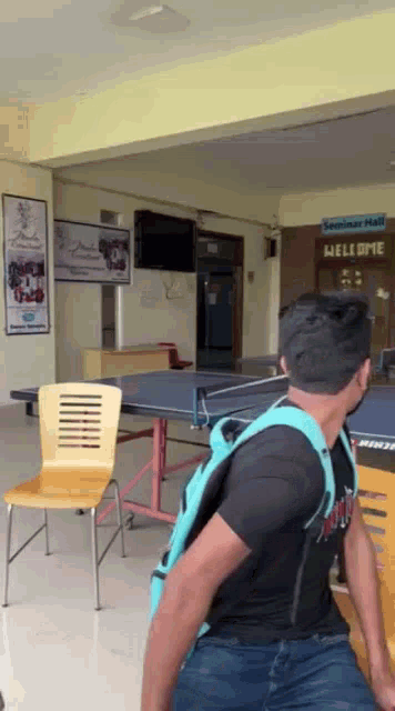 a man with a backpack is sitting in front of a seminar hall sign