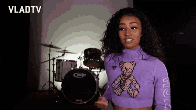 a woman in a purple sweater with a teddy bear on it