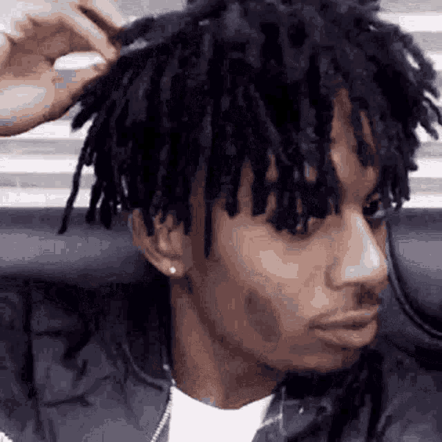 a man with dreadlocks is brushing his hair .