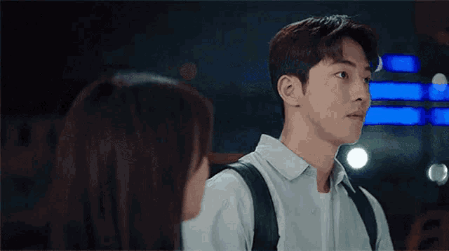 a man and a woman are looking at each other with a backpack on .