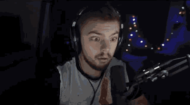 a man wearing headphones and a tie is talking into a microphone in front of a christmas tree .