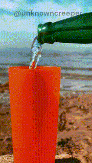 a green bottle is pouring water into a red cup