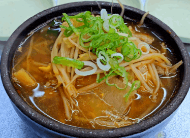 a bowl of soup with noodles and onions on top