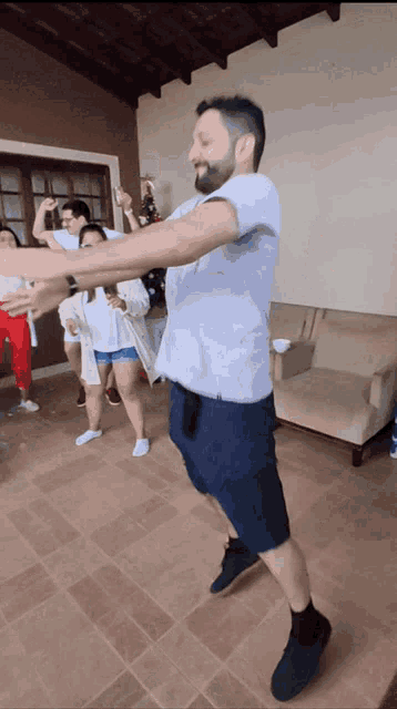 a man in a white shirt and blue shorts is dancing with a group of people